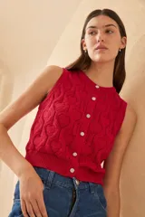 Chaleco de punto color crudo con diseño calado de corazones, sin mangas y con botones joya.