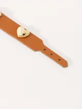 Pulsera marrón de cuero con hebilla dorada y dijes de corazón.