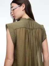 Camisa negra sin mangas con cuello mao y cierre frontal con botones.