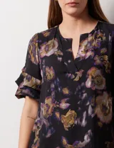 Blusa de gasa estampada con cuello a la base y escote en V. Tiene mangas cortas amplias con sobrecapas.