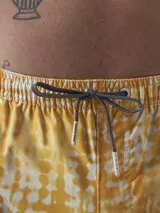 Short de baño verde con estampado de margaritas blancas y cordón ajustable naranja.