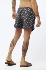 Short de baño con estampado de hojas de palmera en tonos beige, verde y naranja.