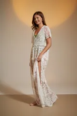 Vestido largo blanco de encaje con diseño de piñas bordadas. Presenta escote en V profundo y mangas cortas holgadas.