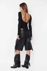 Campera puffer negra de cuero sintético, con cuello alto, cierre frontal con cremallera y bolsillos laterales.