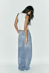 Pantalón de jean celeste de corte extra wide leg, tiro alto, cinco bolsillos, trabillas en la cintura y cierre con cremallera y botón metálico.