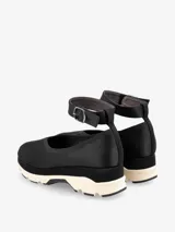 Zapato color marrón con base deportiva, pulsera al tobillo ajustable con hebilla metálica y puntera redondeada.