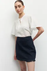 Blusa blanca de manga corta con cuello mao, lazo en el frente y detalles de strass.