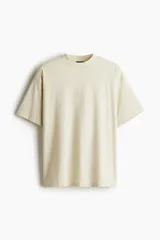 Remera color crema de algodón de peso medio, con cuello redondo ribeteado, hombros caídos, corte oversized y bajo recto.