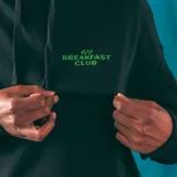 Hoodie negro con bolsillo tipo canguro y estampado frontal con el texto "420 Breakfast Club" en color verde.