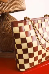 Bolso tipo tote de cuero tejido a mano con diseño a cuadros en color negro y tostado.