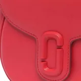 Cartera bandolera Marc Jacobs modelo The Saddle Bag, color negro, de cuero, con cierre de solapa con broche magnético y logo de la marca en el frente. Incluye correa ancha de tela con el nombre de la marca en blanco y negro.