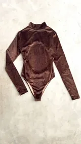 Body de terciopelo marrón con estampado de piel de serpiente, cuello alto, mangas largas con orificio para el pulgar y espalda descubierta.