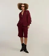Bermuda de sastrería color borgoña, con cierre descentrado, trabillas en la cintura y pliegues delanteros.