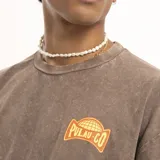 Remera marrón de corte holgado con cuello redondo y estampado pequeño en el pecho con el logo de la marca Pulau.