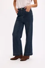 Pantalón de jean azul oscuro de tiro alto, con costuras verticales decorativas en el frente y cierre de botón metálico.