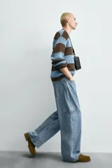 Pantalón de jean celeste de corte holgado y amplio en toda la pierna, tiro medio, tejido rígido, cinco bolsillos, efecto lavado, parche en trasero y bolsillo de vivo en pernera.