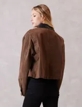 Campera de denim color marrón, con cuello de solapa en ecocuero negro. Cierre frontal con botones y bolsillos delanteros. Forro interno a tono.