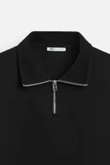 Sudadera negra de cuello alto con cierre frontal de cremallera, corte relaxed fit, manga larga y terminaciones en rib.