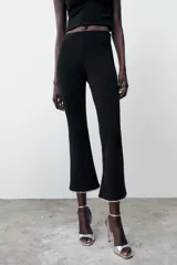 Pantalón negro de tiro alto, corte ajustado y cintura elástica. El ruedo es acampanado y está decorado con perlas.