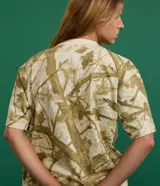 Remera de algodón color crudo con estampado de ramas y hojas en tonos marrones. Corte boxy, cuello redondo y mangas cortas.