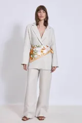Blazer de lino color beige, de corte recto y solapas clásicas. Incluye un pañuelo estampado atado a la cintura.