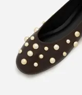 Zapatilla tipo bailarina color marrón con apliques de esferas metálicas doradas. Confeccionada en cuero sintético y sin cierre.