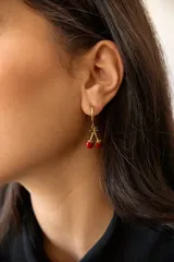 Par de aros plateados con forma de cerezas colgando de un aro pequeño.