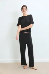 Conjunto de pijama negro, compuesto por una remera de manga corta con detalle de encaje en los puños y un pantalón largo de corte recto.