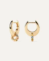 Aros dorados tipo argolla con dije redondo colgante con incrustaciones de circonitas cúbicas multicolores.