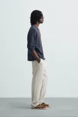 Pantalón color arena de corte recto, confeccionado en tejido de algodón y lino. Cuenta con cintura elástica ajustable con cordón, bolsillos delanteros y traseros de parche.