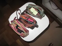 Neceser gris de tela satinada con cierre superior y detalle de moño en el frente.