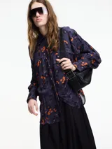 Camisa de viscosa estampada con flores color naranja sobre fondo azul marino. Tiene botones en la parte delantera y lazo ajustable.