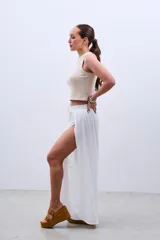 Pantalón blanco de tela fluida con cintura elastizada y cordón ajustable. Presenta aberturas laterales amplias desde la cintura hasta el ruedo.