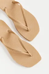 Ojotas color beige con base texturizada y tiras con diseño trenzado y logo de la marca.