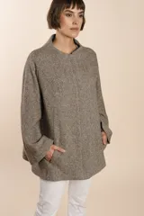 Capa marrón con bolsillos, mangas amplias y pinzas en la delantera. Terminaciones interiores envivadas. Confeccionada en lana fina sin teñir, diseñada exclusivamente por Don Baez.