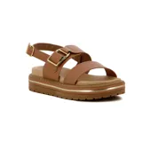 Sandalia de plataforma color negro, con dos tiras anchas sobre el empeine y una tira ajustable con hebilla dorada en el tobillo. La plataforma tiene un detalle de línea dorada.