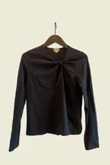 Remera de manga larga color negro, confeccionada en algodón peruano con elastano. Tiene escote redondo y un nudo en el frente que genera una abertura.