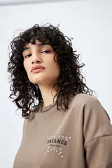 Buzo color marrón de corte relajado confeccionado en tejido de algodón con interior suave al tacto. Presenta detalle de estrella con tachas en la espalda y bordado delantero con la frase Dreamer – Born to rock.