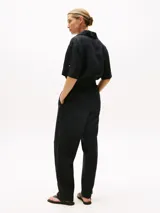 Mono negro de lino con cuello camisero, manga corta, cierre frontal con botones, cinturón con hebilla forrada y bolsillos laterales.