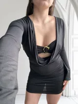 Vestido negro de tres piezas, compuesto por un top tipo corpiño con aro dorado, una falda mini fruncida y un cardigan de mangas largas.