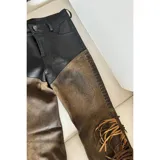 Pantalón de cuero negro y marrón con corte texano y flecos en el lateral.