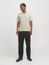 Polo de punto color beige con cierre de cremallera, cuello polo y mangas cortas.