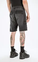 Bermuda cargo de denim negro lavado, de calce regular, con cinco bolsillos y bolsillos cargo laterales. El ruedo es desflecado.