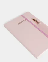 Set de librería que incluye un cuaderno A5 forrado en PU rosa pastel con elástico y una lapicera metálica de tinta negra.