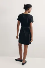 Vestido negro a la rodilla con escote bote y pliegues de caja invertidos adelante y atrás. Modelo de manga corta con cintura entallada, cinturón extraíble con hebilla de metal y bajo recto. Cierre oculto en la espalda. Sin forrar.