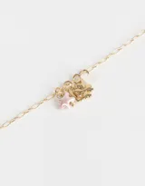 Collar largo dorado con cadena de eslabones y dijes colgantes con forma de trébol de cuatro hojas, estrella y cuenta de cristal.