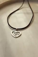 Gargantilla de tiento sintético negro con dije de laberinto con forma de corazón en acero quirúrgico plateado.