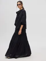 Camisa de broderie de algodón color negro, con cuello mao y cierre de cuatro botones. Presenta mangas abullonadas y galones con transparencias en la parte delantera y mangas.