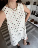 Vestido corto blanco con lunares marrones, sin mangas y cuello redondo.