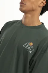 Remera marrón con cuello redondo, corte holgado y estampado pequeño de flores y texto en el pecho.